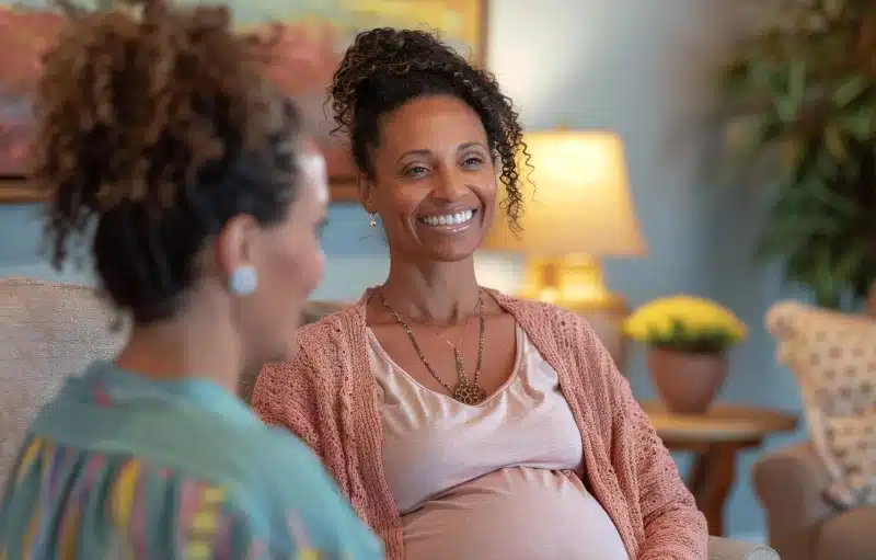 Smiling pregnant woman in conversation with another woman during a support visit at ProHealth Chiropractic Rockville clinic
