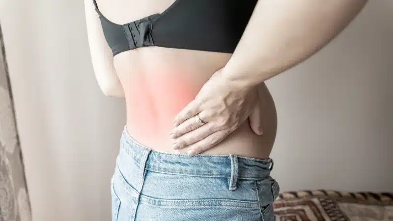 Pregnant woman holding her lower back with pain highlighted at ProHealth Chiropractic Rockville clinic