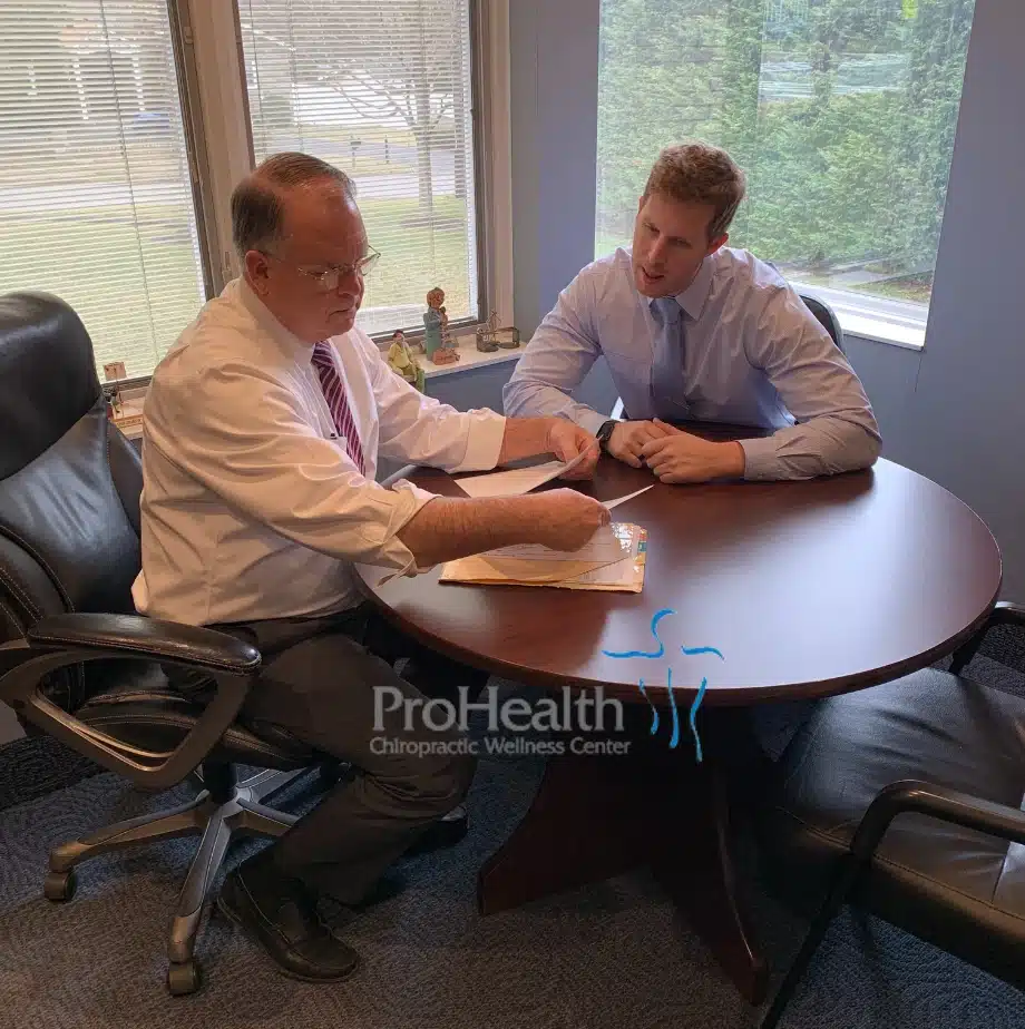 Two chiropractors reviewing paperwork together at a consultation table at ProHealth Chiropractic Rockville clinic