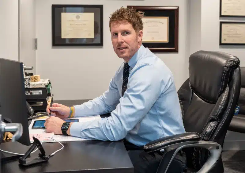 Chiropractor seated at his desk with framed diplomas and credentials on the wall at ProHealth Chiropractic Rockville clinic