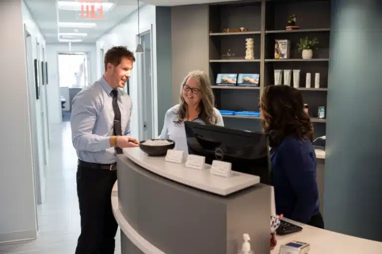 Chiropractor greeting front desk staff and a patient in the hallway at ProHealth Chiropractic Rockville clinic
