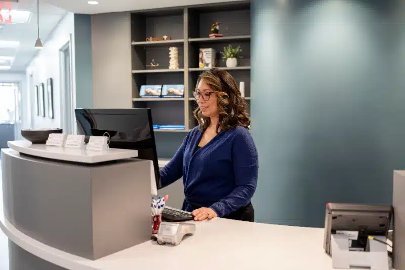 Front desk staff member working at the reception computer at ProHealth Chiropractic Rockville clinic