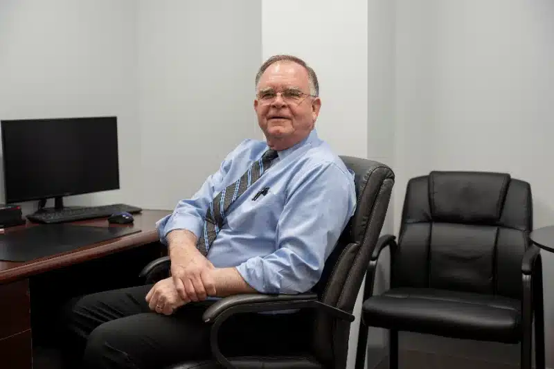 Chiropractor seated in a private consultation office next to an empty patient chair at ProHealth Chiropractic Rockville clinic