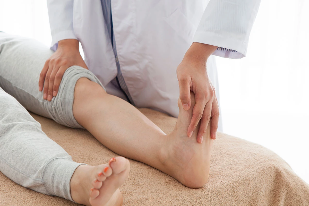 Clinician examining a patient's knee and lower leg during a physical assessment at ProHealth Chiropractic Rockville clinic