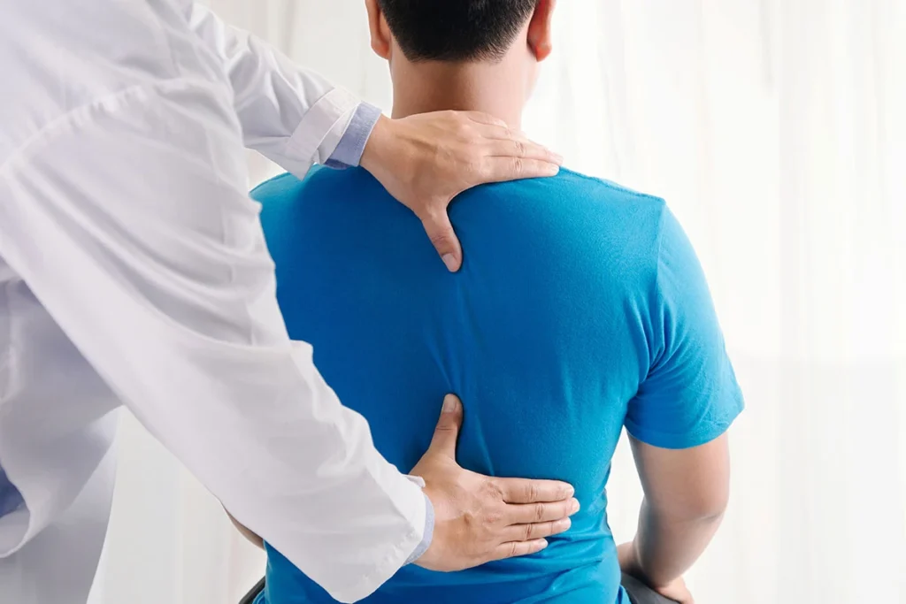 Chiropractor examining a seated patient's upper back at ProHealth Chiropractic Rockville clinic