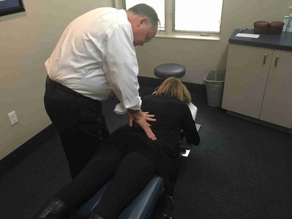 Chiropractor performing a back adjustment on a patient lying face down on a treatment table at ProHealth Chiropractic Rockville clinic