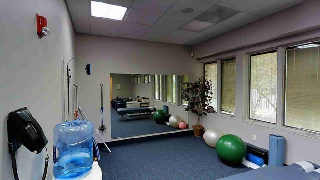 Rehabilitation room with exercise balls, a mirror wall, and a water cooler at ProHealth Chiropractic Rockville clinic