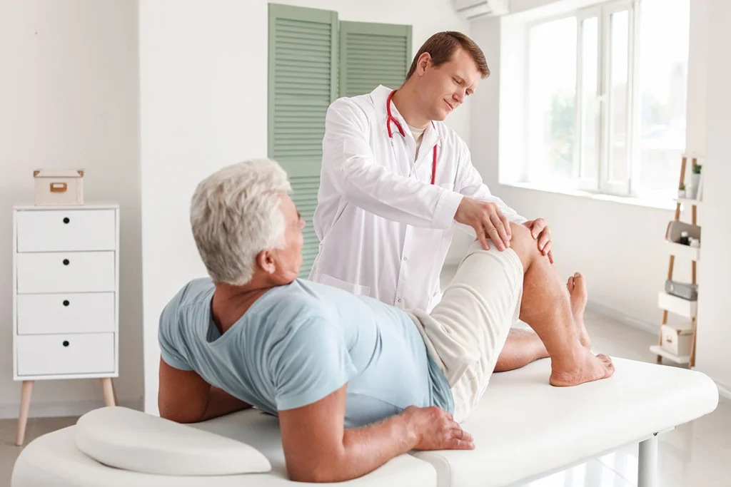 Doctor testing an older patient's knee range of motion during an exam at ProHealth Chiropractic Rockville clinic
