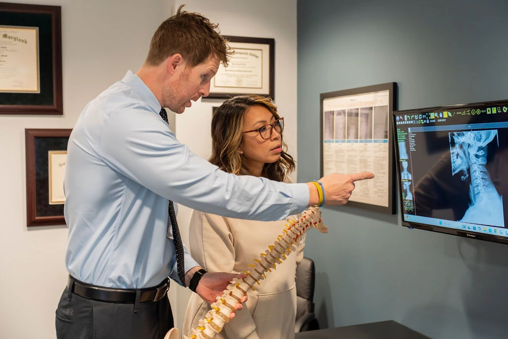Chiropractor reviewing spinal anatomy with a patient during osteoarthritis care in Rockville