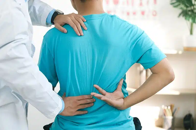 Doctor examining a young patient's spine and shoulder alignment at ProHealth Chiropractic Rockville clinic