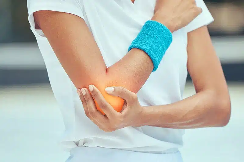 Person holding their inflamed elbow in pain, illustrating tennis elbow, at ProHealth Chiropractic Rockville clinic
