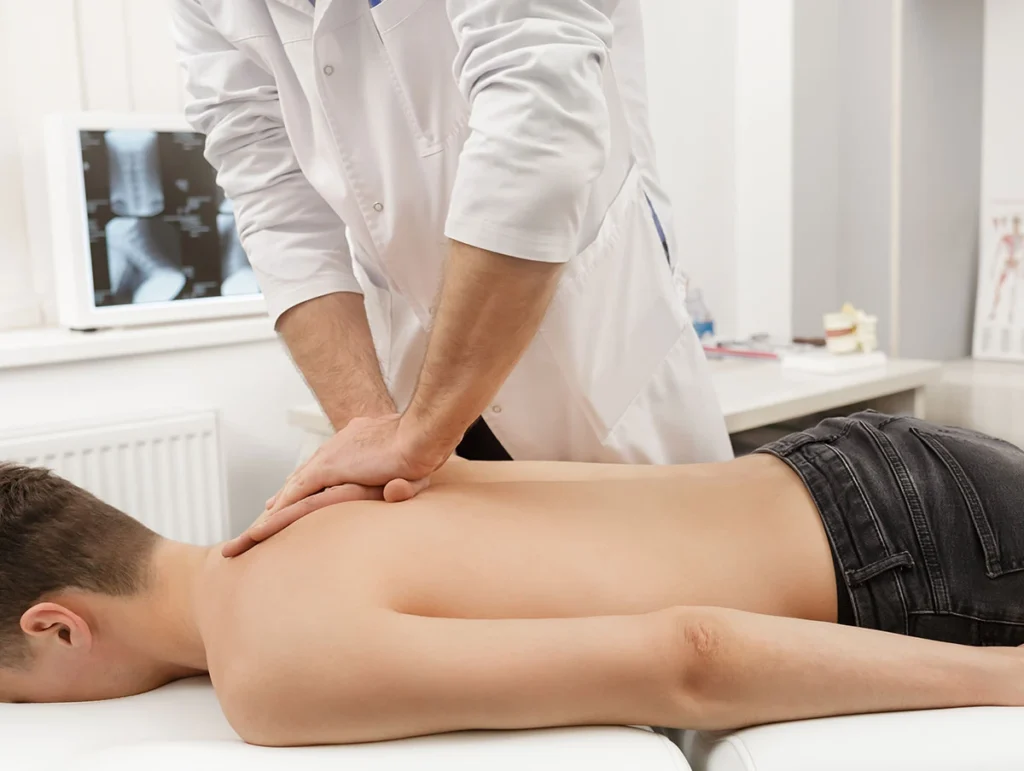 Doctor applying manual pressure to a patient's upper back with a spine X-ray displayed nearby at ProHealth Chiropractic Rockville clinic